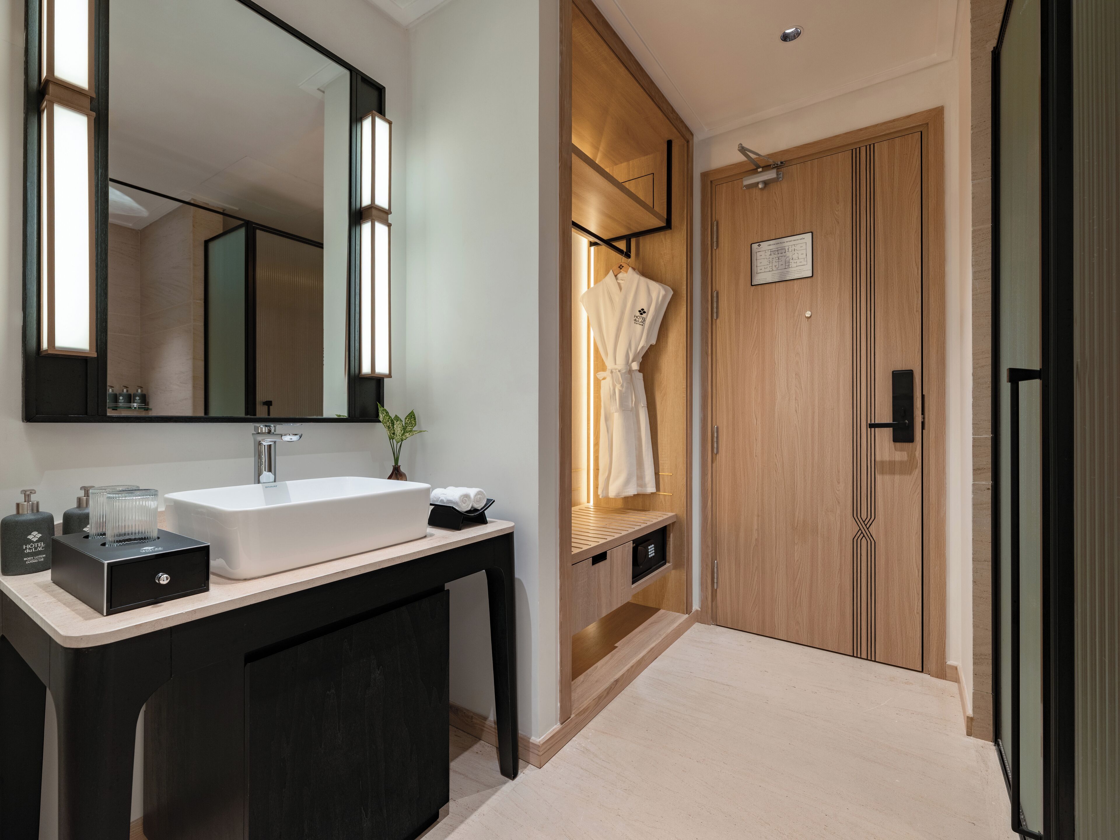 Un baño moderno con un espejo grande, un lavabo blanco y una bata colgada en un perchero.