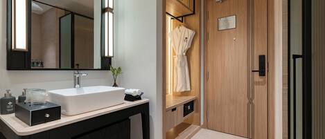 Un baño moderno con un espejo grande, un lavabo blanco y una bata colgada en un perchero.