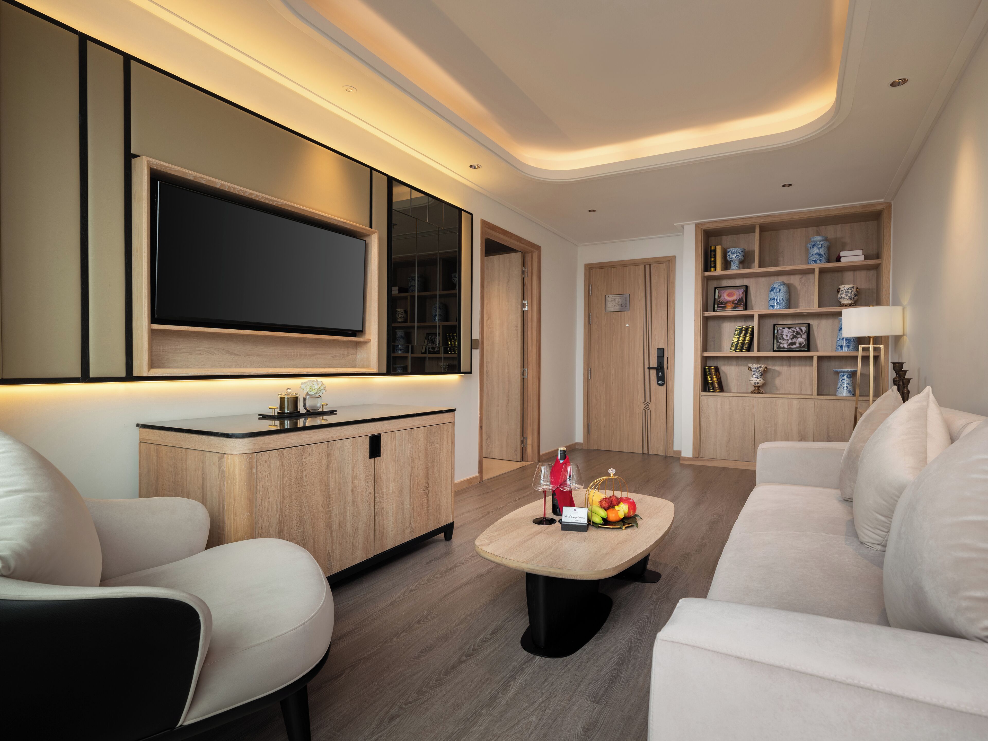 Una sala de estar moderna con un televisor de pantalla plana, un mueble de madera, una mesa de centro con fruta y un sofá.