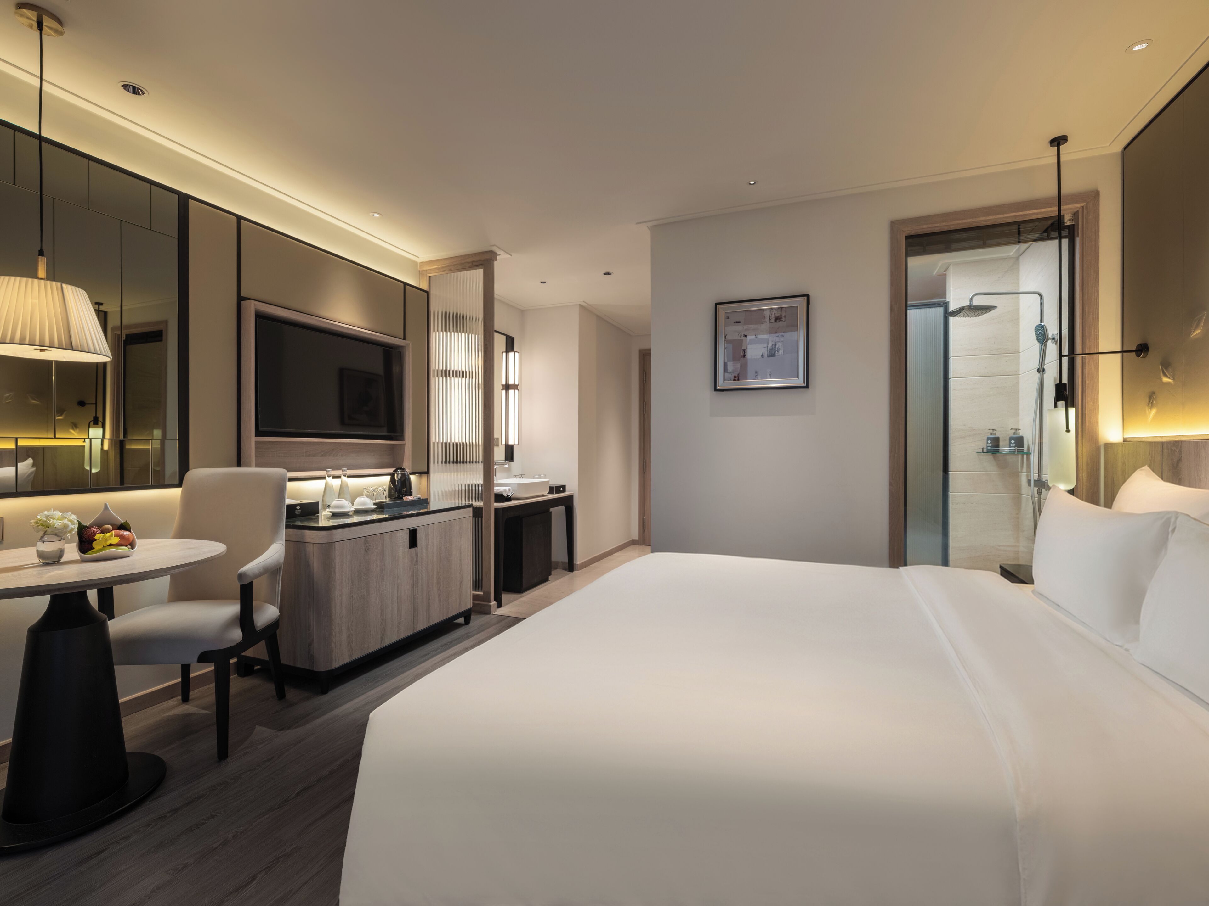 Une chambre d’hôtel moderne dotée d’un grand lit, d’un bureau avec une chaise, d’une petite table avec un vase et d’un espace douche.