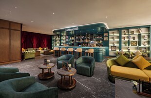 A lounge area with a bar, plush seating, and a display of decorative items.