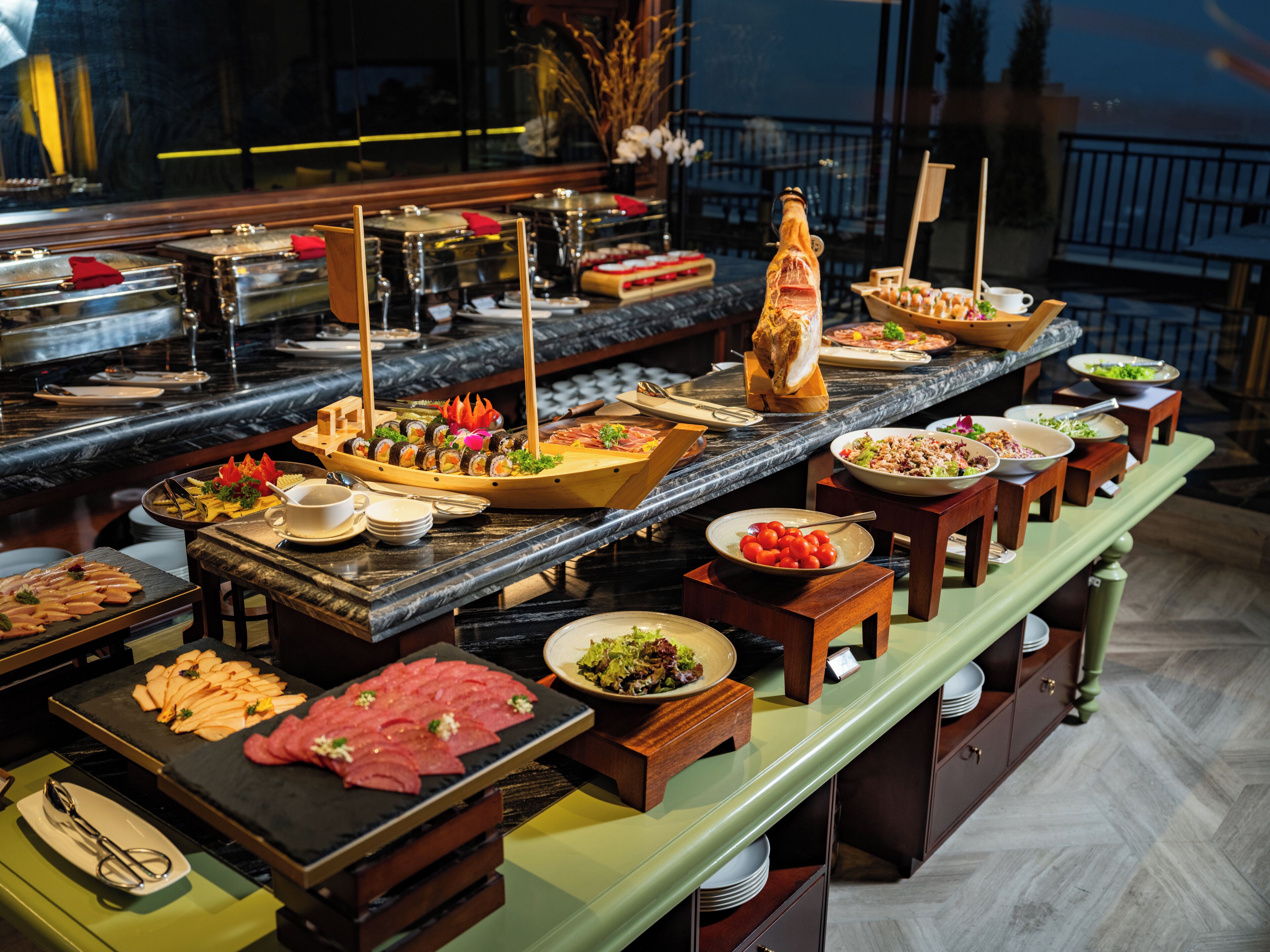 Un buffet proposant une variété de plats, notamment des sushis, des salades et des viandes, disposés sur un comptoir en marbre.
