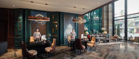 A spacious lobby with a reception desk, seating area, and large windows offering a view of the street.