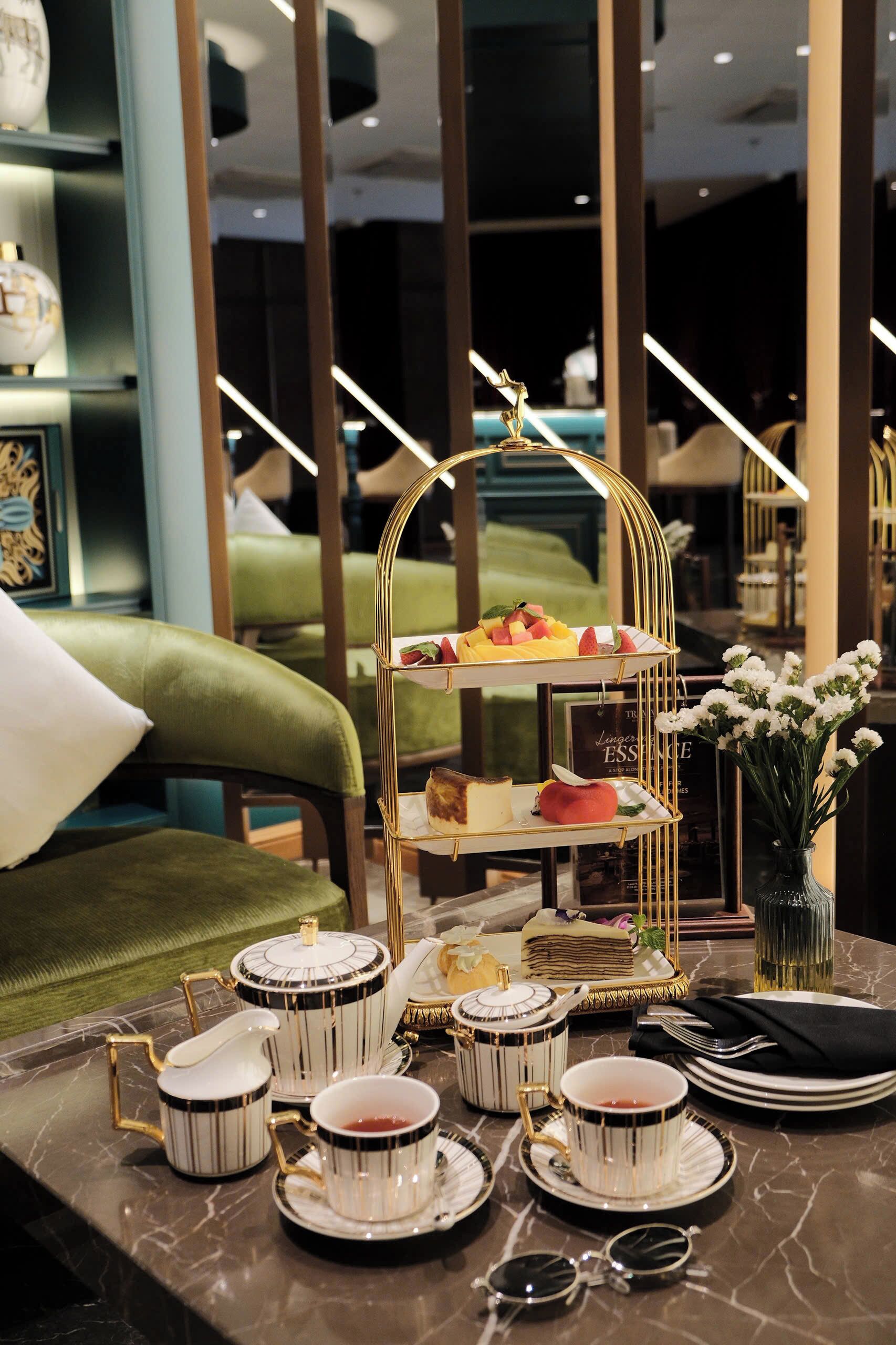 A dining table with a three-tiered dessert stand, tea service, and a vase with flowers.