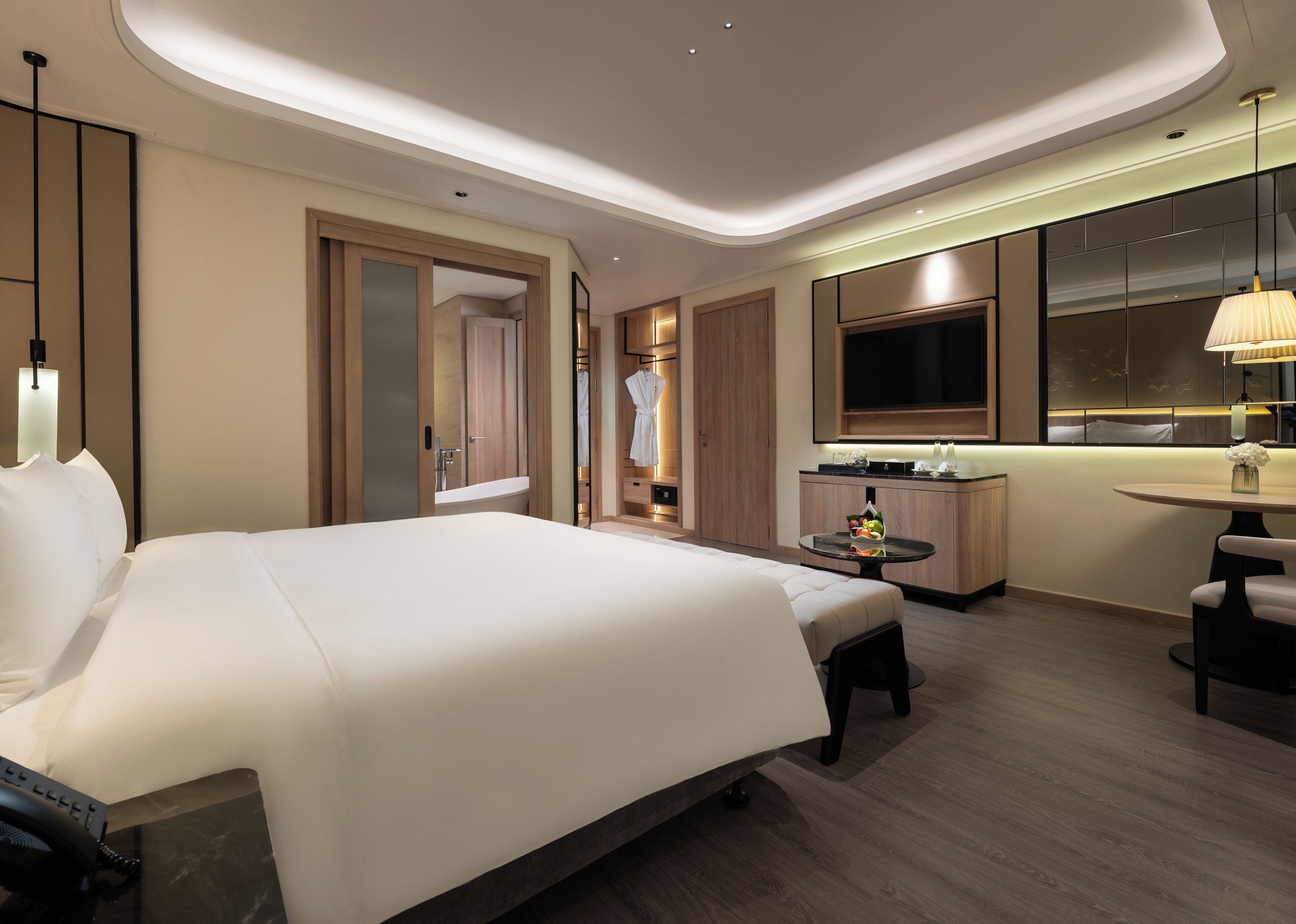 A modern hotel room with a large bed, a desk, and a seating area.