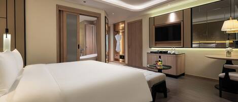A modern hotel room with a large bed, a desk, and a seating area.