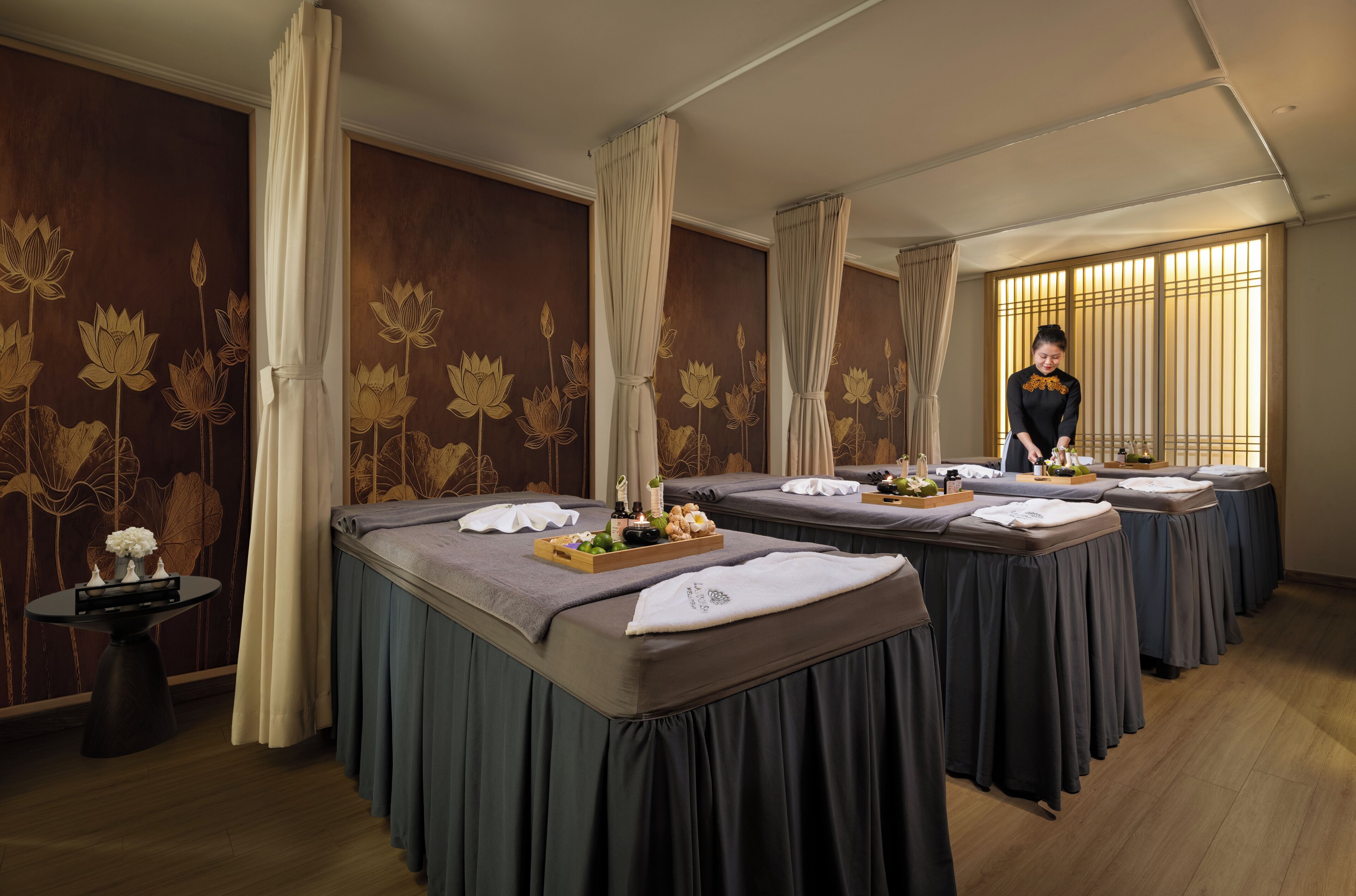 A room with massage tables, each with a towel and a tray of amenities.