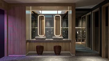 Un baño moderno con dos espejos iluminados, encimera de piedra y detalles de madera.