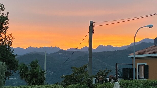 Une piscine avec vue sur les montagnes au coucher du soleil.