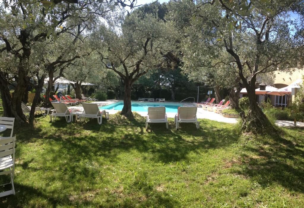 A pool area with lounge chairs and trees.