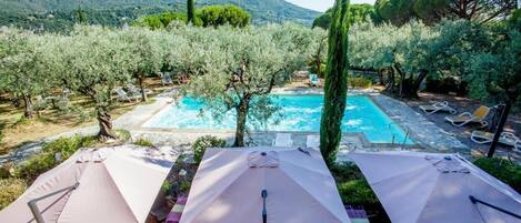 Una piscina al aire libre de temporada, sombrillas