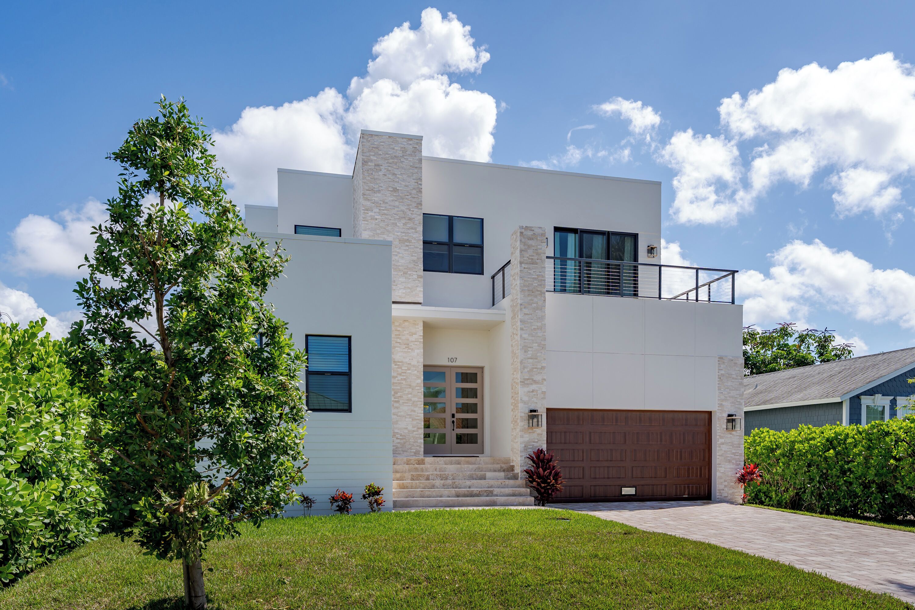A modern two-story house with a garage, a balcony, and a well-maintained lawn.