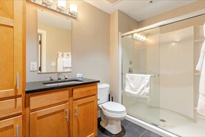 Ein modernes Badezimmer mit Holzschränken, einer Glasdusche und einer weißen Toilette.