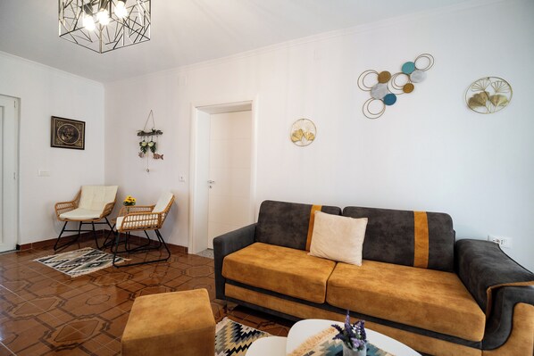 A living room with a sofa, chairs, a patterned rug, and wall decorations. - Villa Balani (Shiroka)