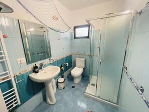 A bathroom with a sink, two toilets, a shower, and a mirror. - Villa Balani (Shiroka)