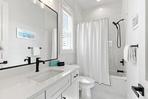 Une salle de bain moderne avec un lavabo blanc, un robinet noir et une douche avec un rideau.