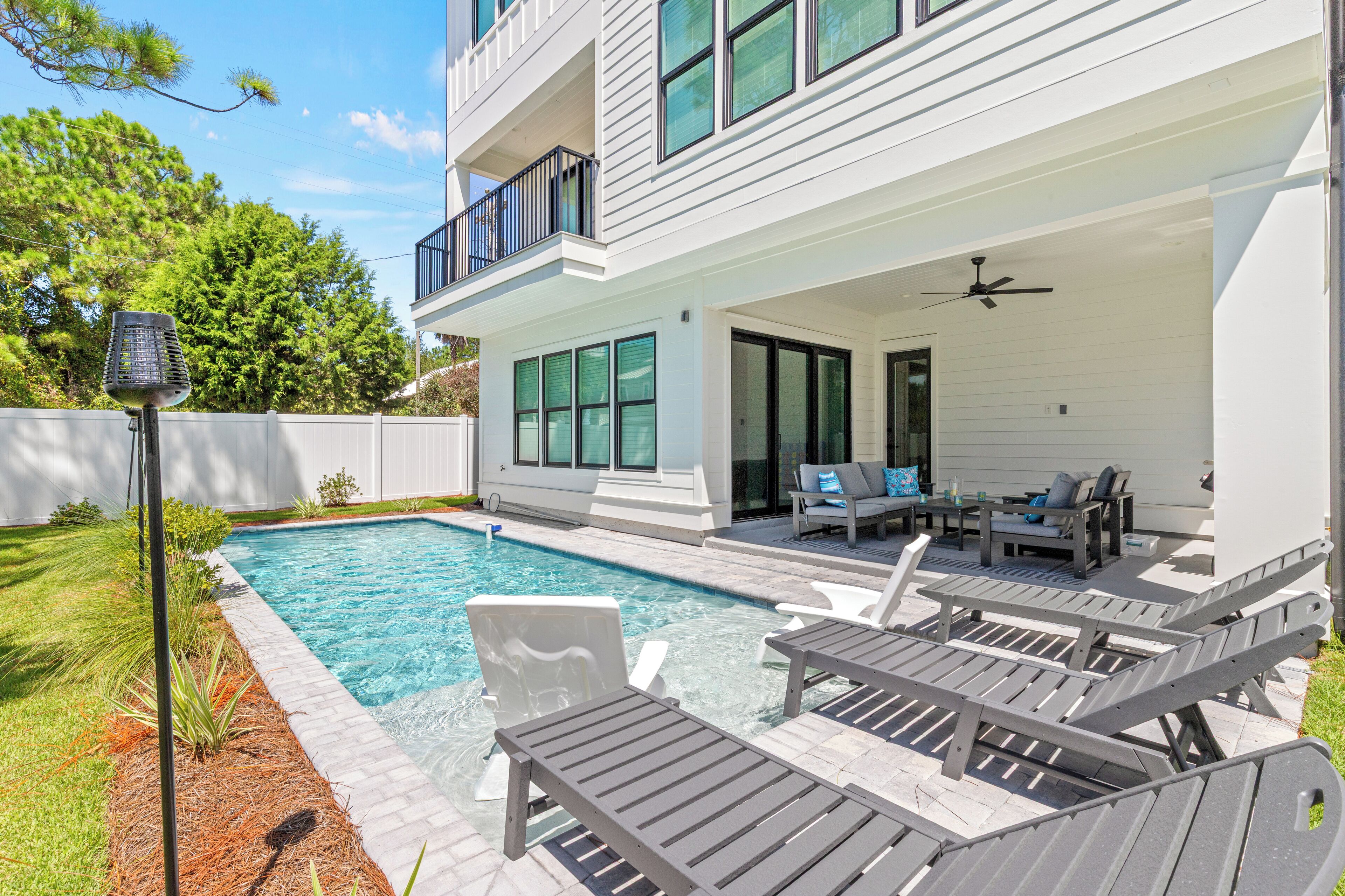 A modern two-story house with a swimming pool, outdoor seating area, and a covered patio.
