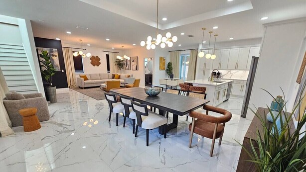 A spacious living area with a large dining table, comfortable seating, and a modern kitchen in the background.