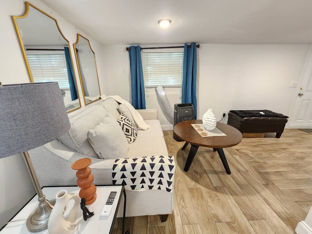 A modern living room with a sofa, a coffee table, a lamp, and a mirror.