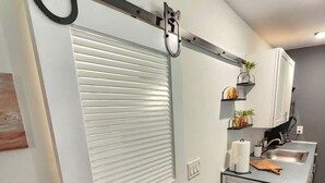 Una cocina compacta con una puerta corredera, una pequeña encimera y un lavamanos.