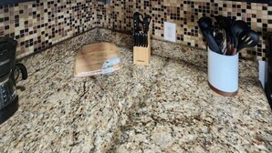 Una cocina con gabinetes negros, encimera de granito y salpicadero de azulejos.