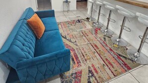 Una sala de estar moderna con un sofá azul, una alfombra estampada y una lámpara de techo original.