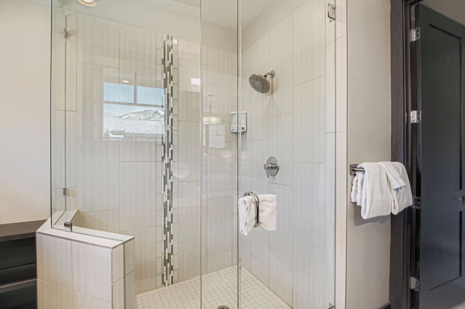 A modern bathroom with a glass-enclosed shower, a white sink, and a towel rack.
