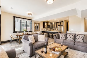 A modern living room with a dining area, kitchen, and large windows. - Tranquil Blackstone 3688 Getaway Walk to Cabriolet Lift (Park City)