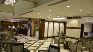 A hotel lobby with a check-in counter, seating area, and a chandelier.