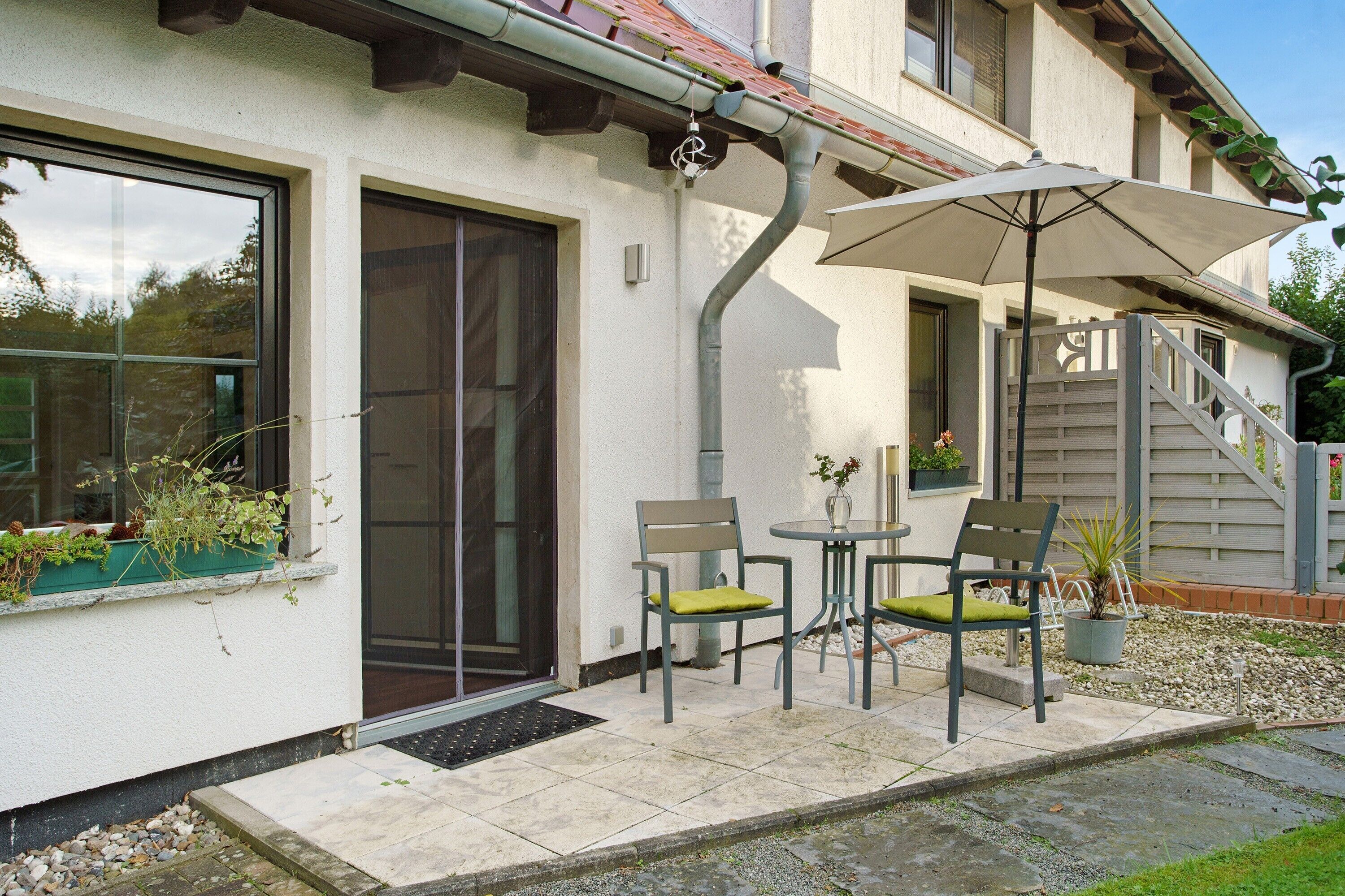 A house with a covered patio, a sliding glass door, and a staircase leading to an upper level.