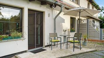 A house with a covered patio, a sliding glass door, and a staircase leading to an upper level.