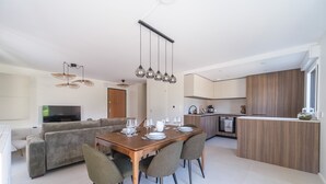 A modern kitchen with a dining area, a sofa, and a TV.