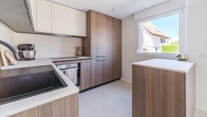 A modern kitchen with wooden cabinets, a built-in oven, and a window with a view of the outside.