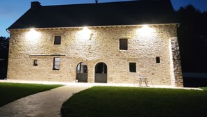 Un edificio de piedra con entrada central, dos accesos laterales y un pequeño balcón.