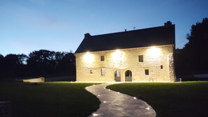 Un edificio de piedra con un camino empedrado que lleva a la entrada, rodeado de césped.