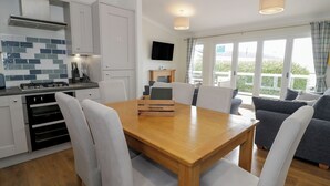 A modern kitchen with white cabinets, a tiled backsplash, and a built-in oven. - Platinum Lodge (Talybont)