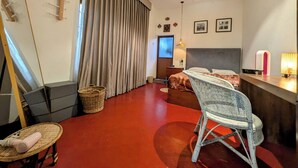 A compact hotel room with a bed, a desk, a chair, and a large window with curtains. - Nomads Hideaway Near Matara Railway Stat (Matara)