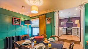 A dining area with a wooden table set for breakfast, a radiator, and a view into the kitchen. - Harbour Master, Whitstable, Kent (Whitstable)
