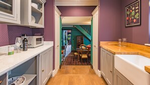 A narrow kitchen with white cabinets, a wooden floor, and a purple wall. - Harbour Master, Whitstable, Kent (Whitstable)
