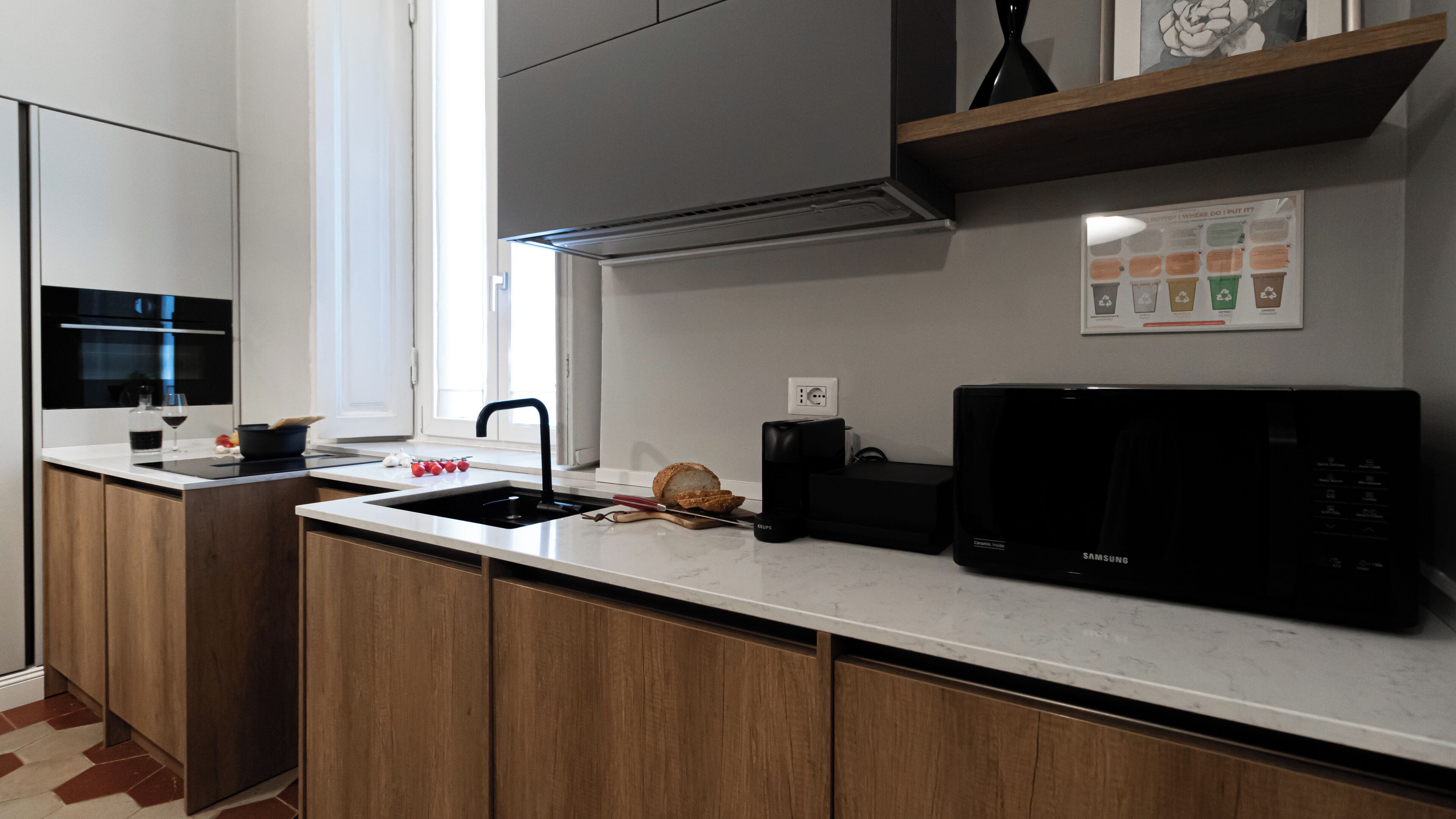 Een moderne keuken met een ingebouwde magnetron, een spoelbak en houten keukenkastjes.
