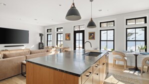 A modern kitchen with a large island, wooden cabinets, and pendant lighting. - Upscale 4Bdrm Getaway with Hot Tub, Near Stowe Village & Trails (Stowe)