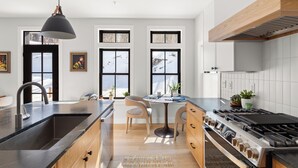 A modern kitchen with a central island, a built-in stove, and a large window. - Upscale 4Bdrm Getaway with Hot Tub, Near Stowe Village & Trails (Stowe)