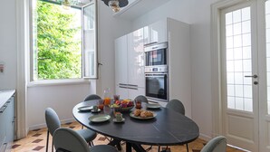 A modern kitchen with white cabinets, a black countertop, and a dining area with a round table and chairs.