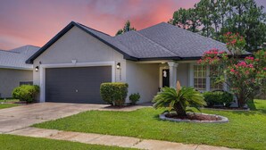 A residential house with a garage, a well-maintained lawn, and flowering plants. - The Dive Locker- 5 min to the Beach Sleeps 10 (Panama City Beach)