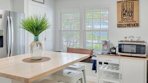 A modern kitchen with a wooden table, a refrigerator, a microwave, and a coffee maker. - The Dive Locker- 5 min to the Beach Sleeps 10 (Panama City Beach)