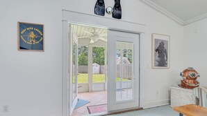 A room with a sliding glass door leading to a backyard, a ceiling fan, a framed picture, and a vintage diving helmet. - The Dive Locker- 5 min to the Beach Sleeps 10 (Panama City Beach)