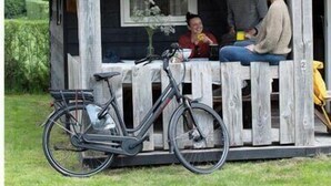 A wooden cabin with a porch, a bicycle, and a small table.