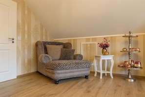 A room with a leopard print armchair, a small white table with a vase, and a multi-tiered stand with decorative items. - Apartment 'Am Wäldchen' with Shared Terrace, Shared Garden and Wi-Fi (Vöhl)