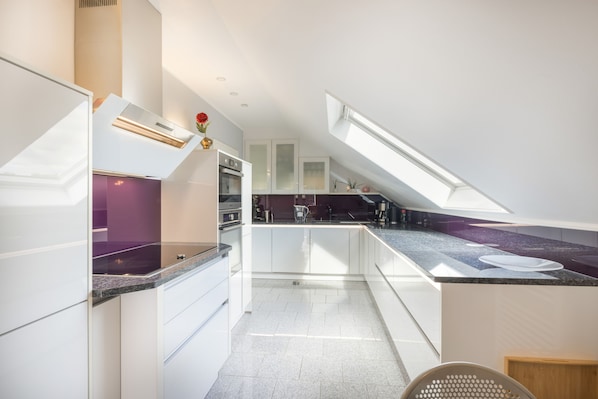 Una cocina moderna con tragaluz, armarios blancos y encimeras de granito.