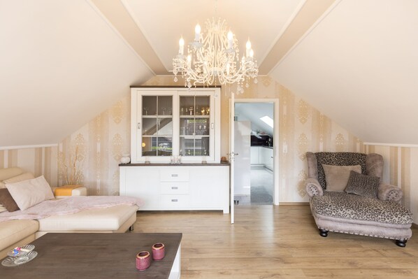 A cozy living room with a sofa, a leopard print armchair, a coffee table, and a chandelier.